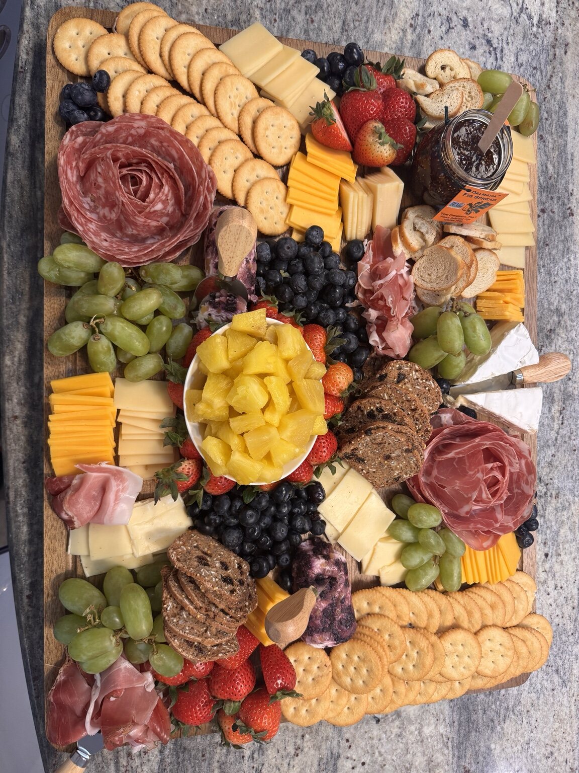 Abundant charcuterie board with meats, cheeses, crackers, and fruit