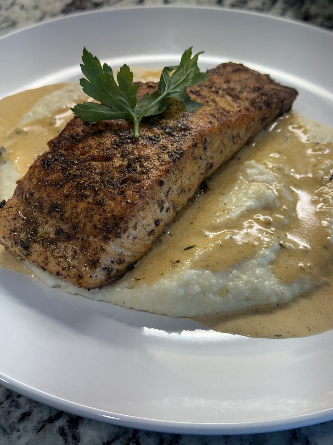Seasoned salmon served over creamy grits